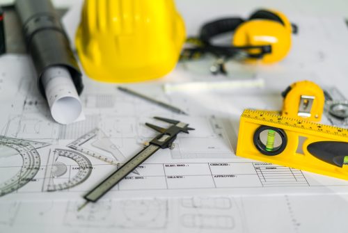 Construction plans with helmet and drawing tools on blueprints
